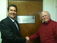 Cayuga Radio Group VP/GM Chet Osadchey, left, dedicates the cluster's conference room to Rudy Paolangeli. [Click for 2012 story]